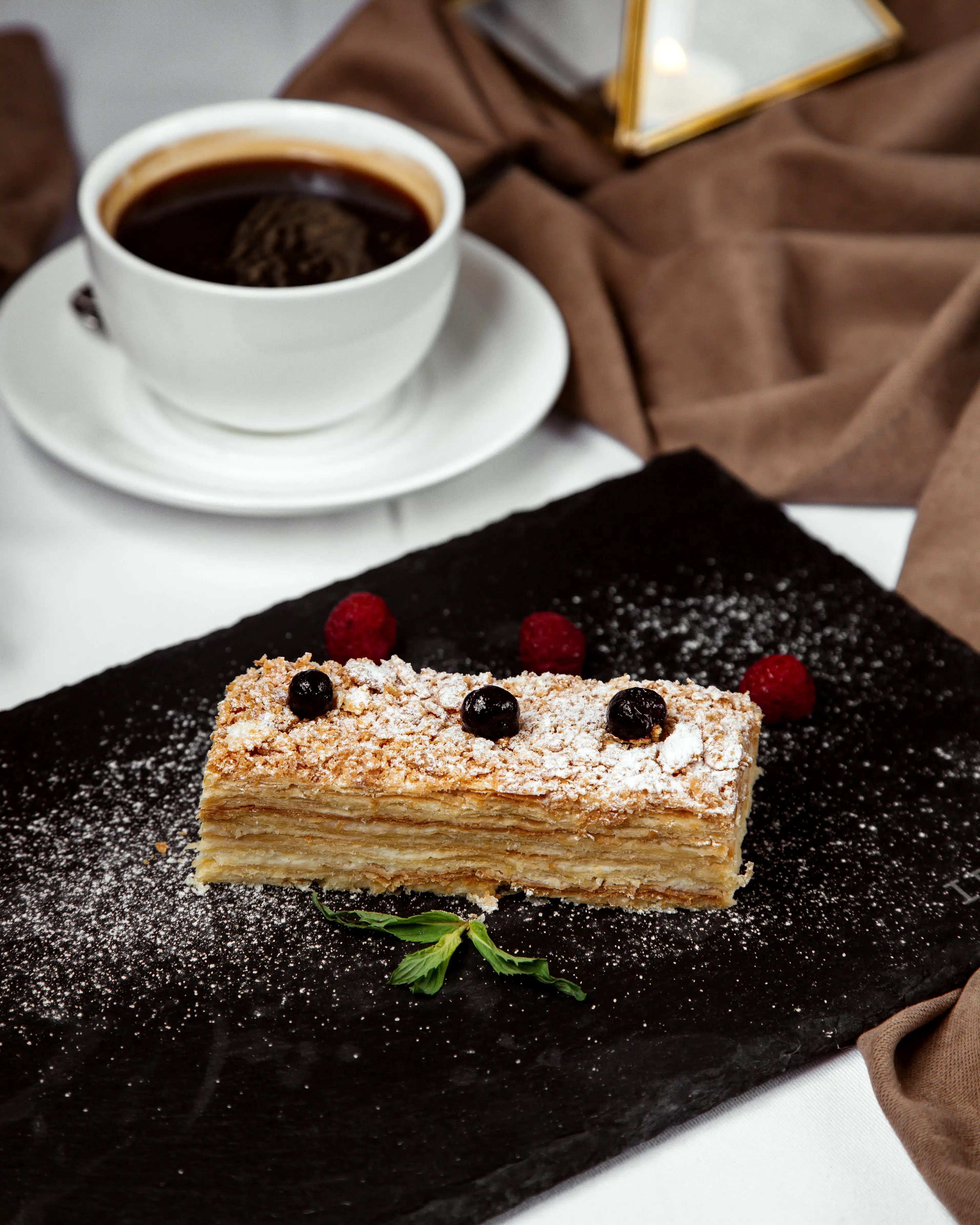 napoleon cake piece garnished with sugar powder, served with black tea Logo Café Luckner